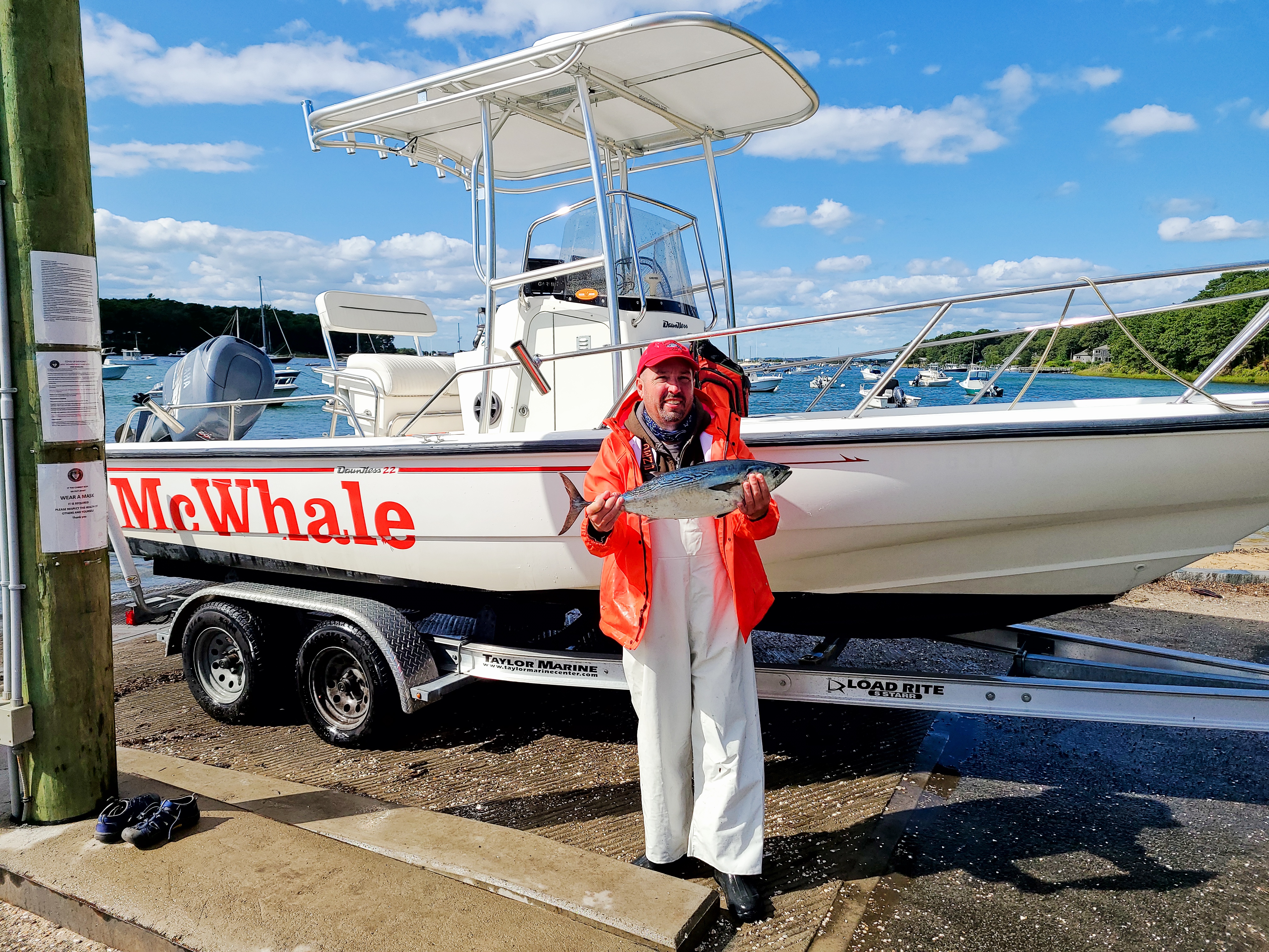 Angler holding a fish beside a boat with a multi-rod T-Top
